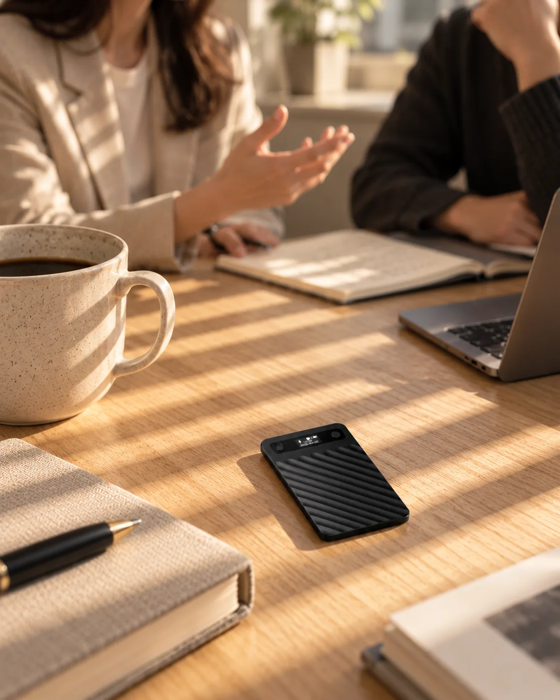 The recorder on an oak meeting table between a coffee cup and notebooks